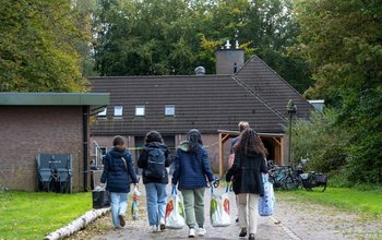 Bewoners van een azc onderweg met boodschappen. Bewoners van een opvangcentrum lopen met boodschappentassen terug naar het gebouw.