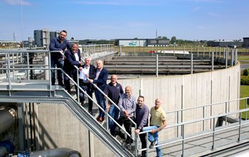 De mensen van  mensen van Waterschap Rivierenland, Omgevingsdienst Rivierenland en gemeente Neder-Betuwe poseren samen bij de waterzuiveringsinstallatie.