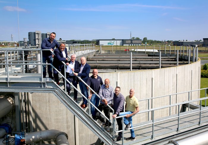 De mensen van  mensen van Waterschap Rivierenland, Omgevingsdienst Rivierenland en gemeente Neder-Betuwe poseren samen bij de waterzuiveringsinstallatie.